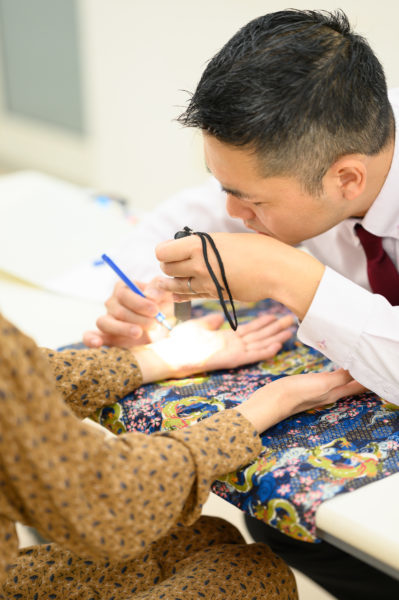 海老名を拠点に活動する手相鑑定師・後藤のプロフィール写真。細部まで読み解く精密鑑定の様子