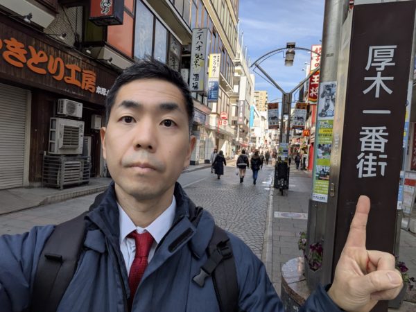 本厚木一番街の看板に指を指す占い師後藤