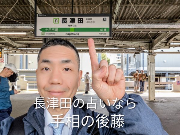 長津田駅の看板前でポーズをとる手相占い師の後藤。長津田周辺で占いの相談なら。