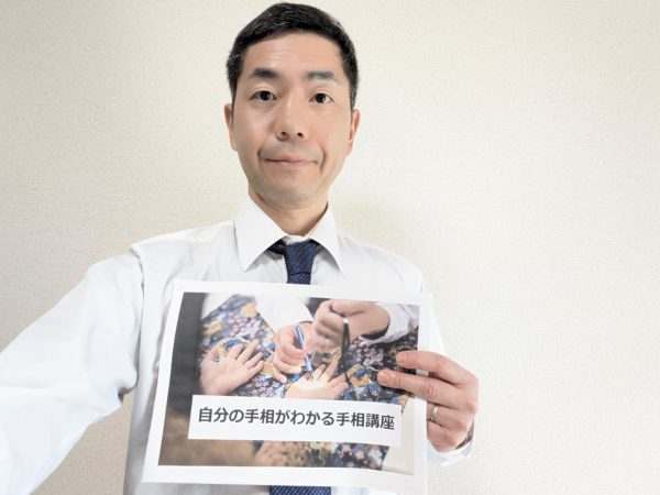 「自分の手相がわかる手相講座」と書かれたテキストを掲げる手相占い師後藤氏のセルフィー。手相講座の告知画像。