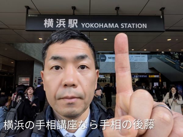 横浜駅で横浜駅の看板を指さす占い師の手相の後藤